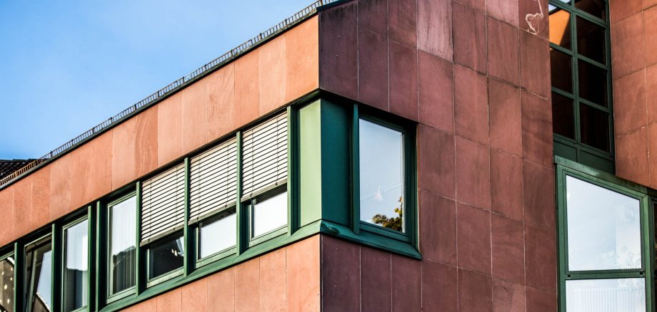 Детайлен изглед на червена сграда със зелени прозорци