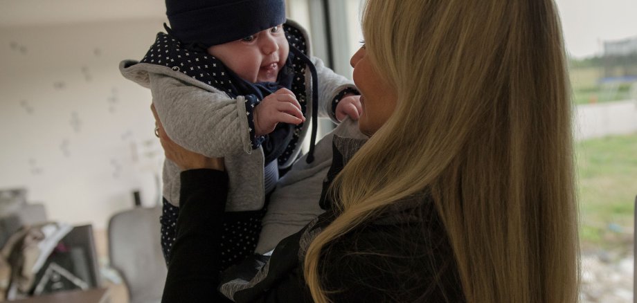 A mother holds up her baby