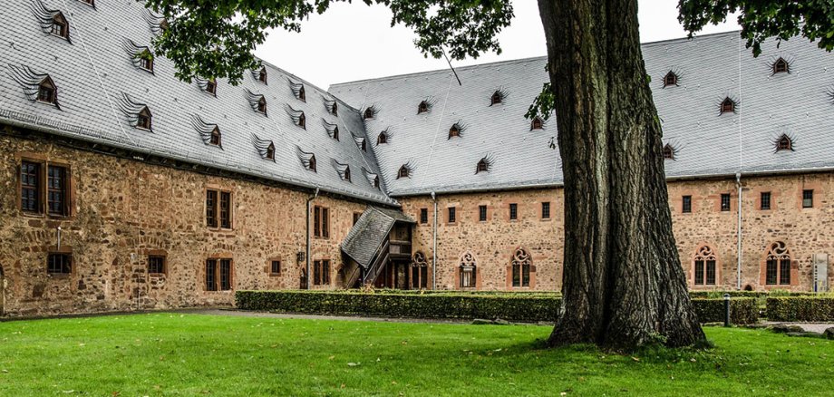 Baum auf Wiese in einem Innenhof eines alten Klostergebäudes